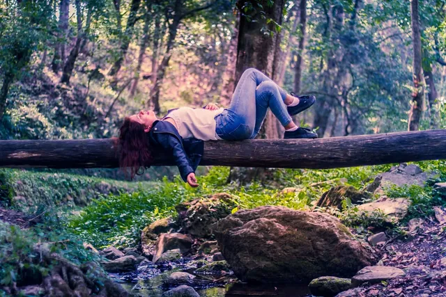 Frau ruht auf einem Baumstamm im Wald